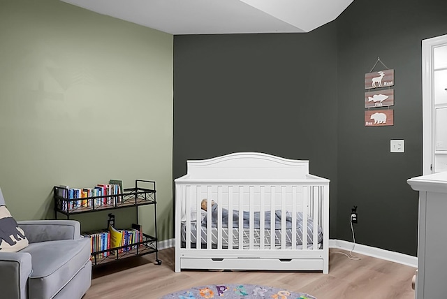 bedroom featuring hardwood / wood-style floors and a nursery area