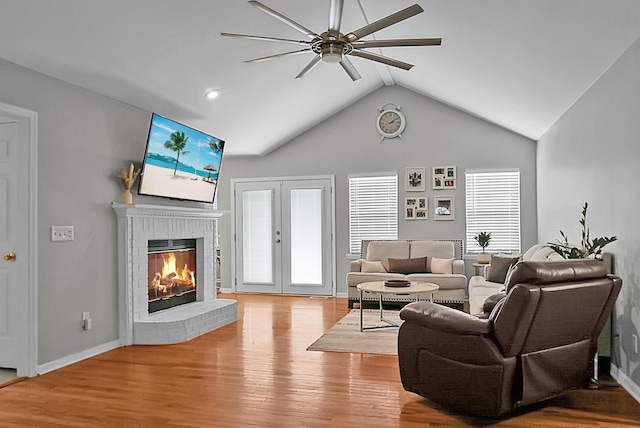 living room featuring french doors, plenty of natural light, a fireplace, and light hardwood / wood-style floors