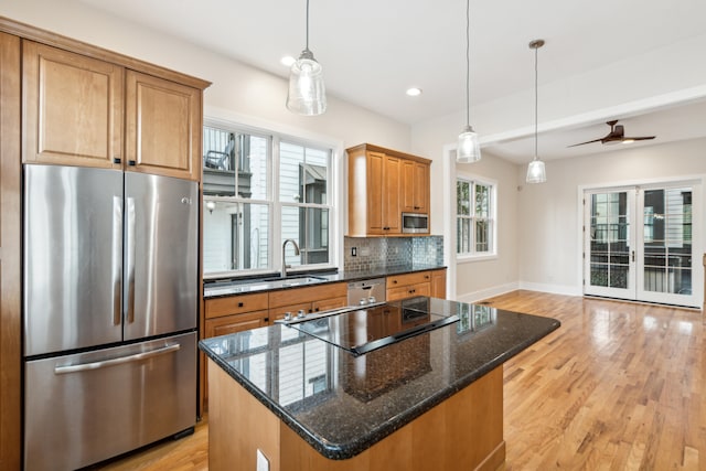 kitchen with stainless steel appliances, hanging light fixtures, light hardwood / wood-style floors, and a center island