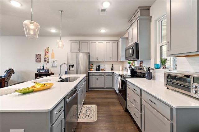 kitchen featuring gray cabinets, sink, stainless steel appliances, and hanging light fixtures