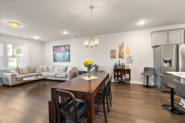 dining area with dark hardwood / wood-style floors and a notable chandelier