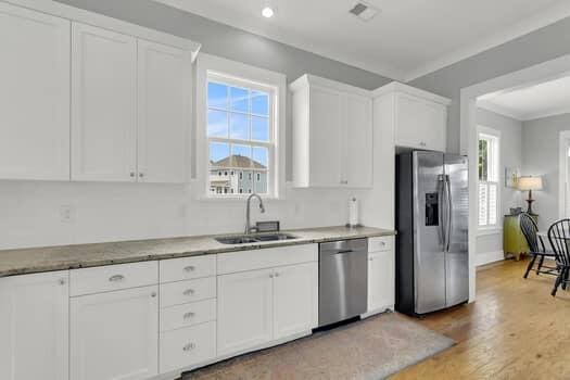 kitchen with appliances with stainless steel finishes, sink, hardwood / wood-style floors, and white cabinets