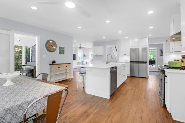 kitchen with light countertops, under cabinet range hood, white cabinets, a ceiling fan, and stainless steel appliances