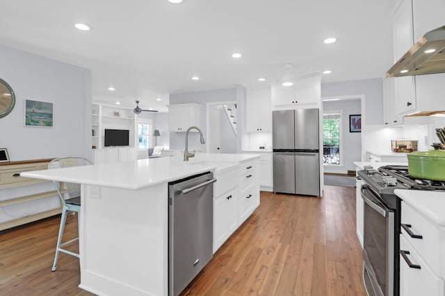 kitchen featuring light wood finished floors, appliances with stainless steel finishes, extractor fan, and ceiling fan
