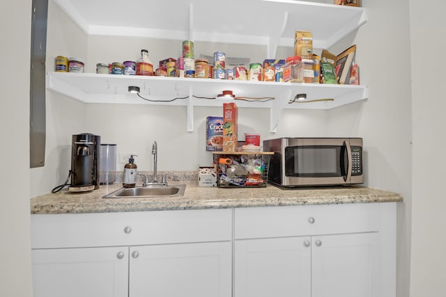 bar with a sink, stainless steel microwave, and wet bar
