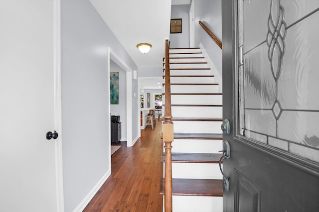 foyer entrance with wood-type flooring, baseboards, and stairway