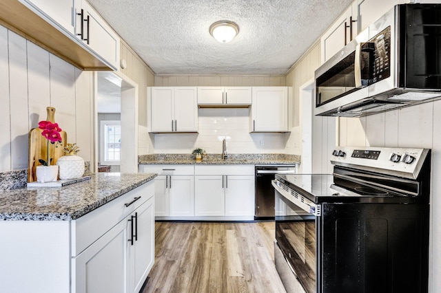 2674 Houston St, North Charleston, SC 29405 - kitchen with appliances with stainless steel finishes, a sink, light wood-type flooring, white cabinetry, and a textured ceiling