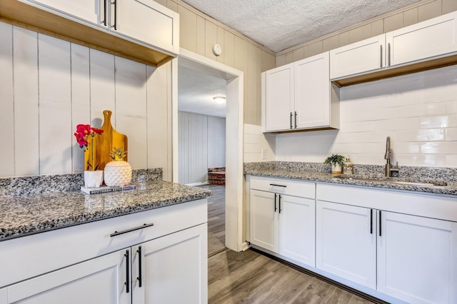 2674 Houston St, North Charleston, SC 29405 - kitchen featuring a textured ceiling, a sink, light wood-style flooring, stone counters, and white cabinetry