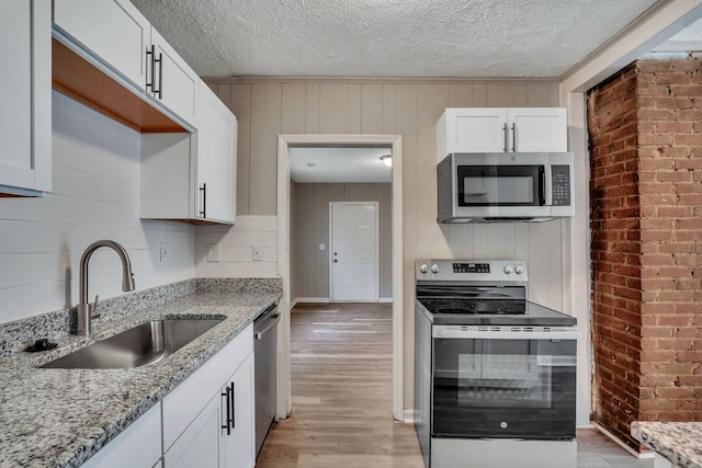 kitchen featuring a sink, a textured ceiling, white cabinetry, appliances with stainless steel finishes, and light wood finished floors