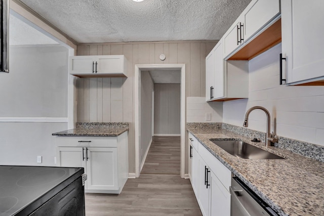 kitchen featuring light stone countertops, white cabinetry, light wood-type flooring, and a sink