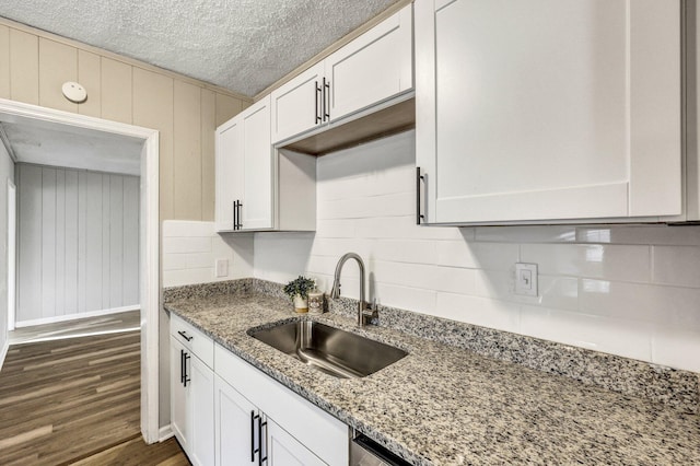 2674 Houston St, North Charleston, SC 29405 - kitchen with a sink, dark wood-type flooring, light stone countertops, white cabinetry, and a textured ceiling