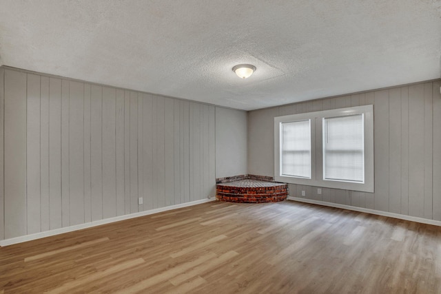 empty room with wood finished floors, baseboards, and a textured ceiling