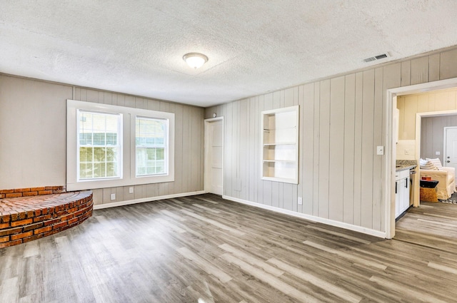 2674 Houston St, North Charleston, SC 29405 - unfurnished living room with wood finished floors, baseboards, wooden walls, and a textured ceiling