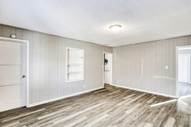 2674 Houston St, North Charleston, SC 29405 - spare room with wood finished floors, a textured ceiling, wood walls, baseboards, and built in shelves
