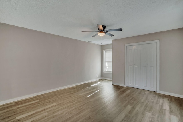 unfurnished bedroom featuring a closet, baseboards, a textured ceiling, and wood finished floors