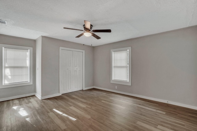 unfurnished bedroom featuring ceiling fan, baseboards, wood finished floors, a closet, and a textured ceiling