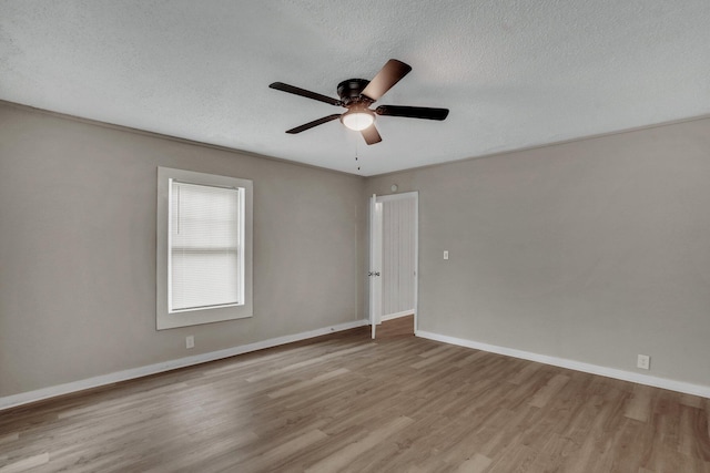 spare room with baseboards, a textured ceiling, wood finished floors, and a ceiling fan