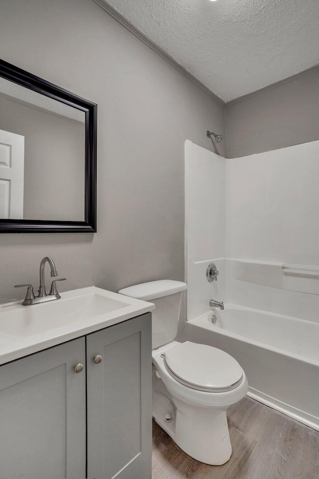 bathroom featuring toilet, wood finished floors, vanity, and a textured ceiling