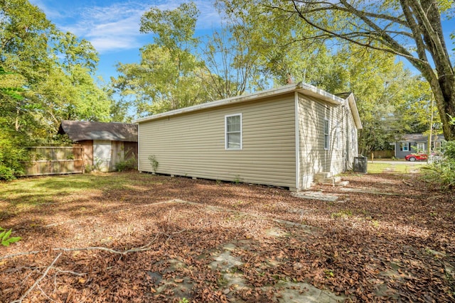 view of property exterior with central AC unit and fence