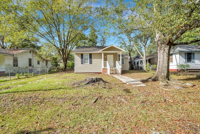 bungalow-style home with a front lawn and fence