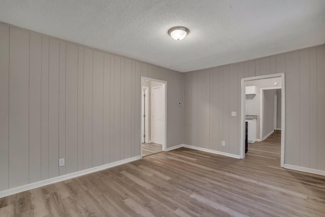 unfurnished room featuring baseboards, a textured ceiling, and wood finished floors