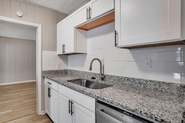 kitchen with white cabinets, light wood-style floors, backsplash, and a sink