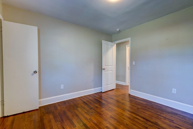 spare room featuring baseboards and wood finished floors