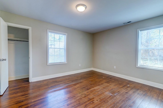 unfurnished bedroom featuring visible vents, a closet, hardwood / wood-style flooring, and baseboards