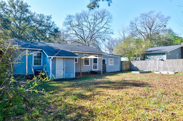 rear view of property featuring fence and a yard