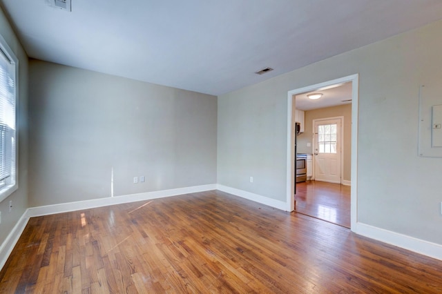 empty room featuring wood-type flooring, visible vents, and baseboards