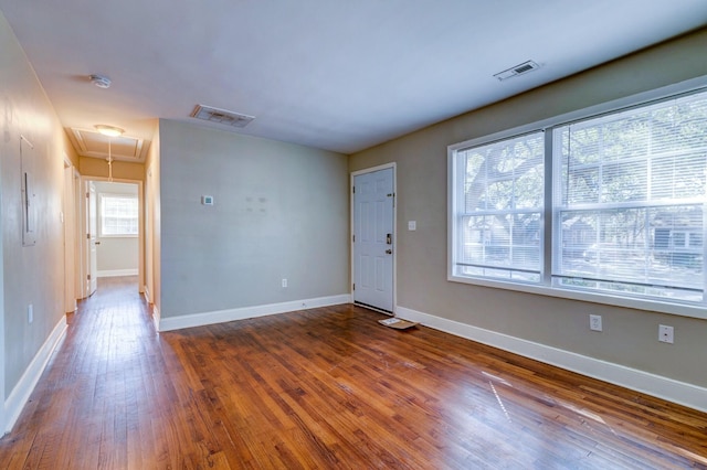 unfurnished room with attic access, visible vents, baseboards, and hardwood / wood-style flooring