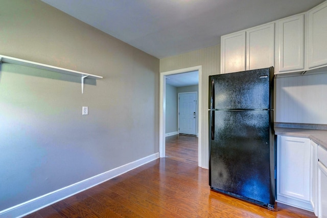 kitchen featuring baseboards, white cabinetry, wood finished floors, and freestanding refrigerator