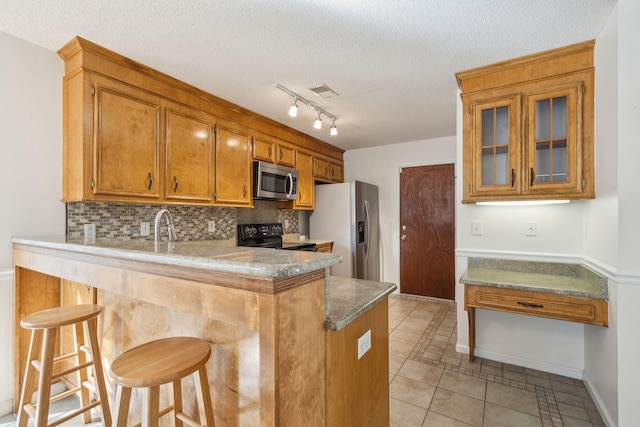 kitchen with a peninsula, appliances with stainless steel finishes, a breakfast bar, and tasteful backsplash