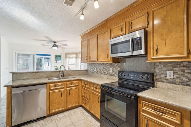 kitchen with stainless steel appliances, a peninsula, a sink, and brown cabinets