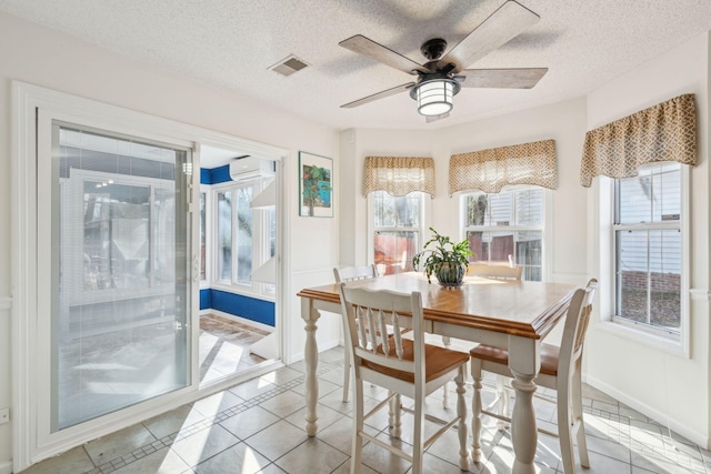 sunroom featuring ceiling fan, a wealth of natural light, a wall mounted air conditioner, and visible vents