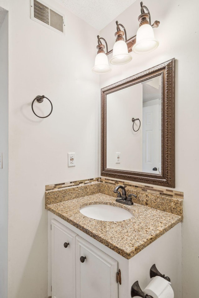 bathroom featuring visible vents, a textured ceiling, and vanity