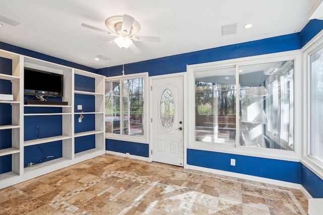 interior space featuring a ceiling fan, stone finish floor, and baseboards