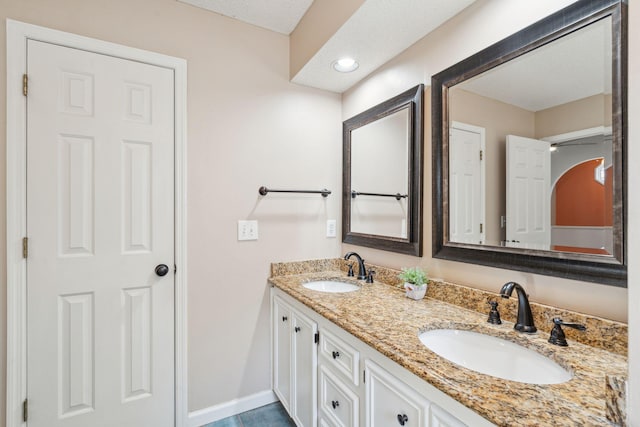 bathroom featuring a sink, baseboards, and double vanity