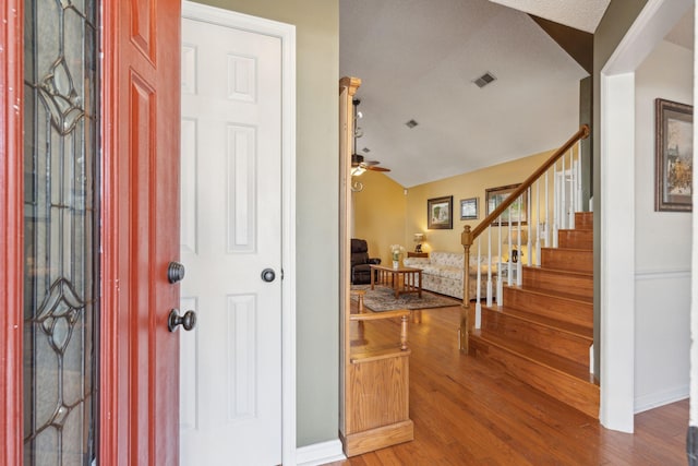 entryway with visible vents, a ceiling fan, lofted ceiling, wood finished floors, and stairs