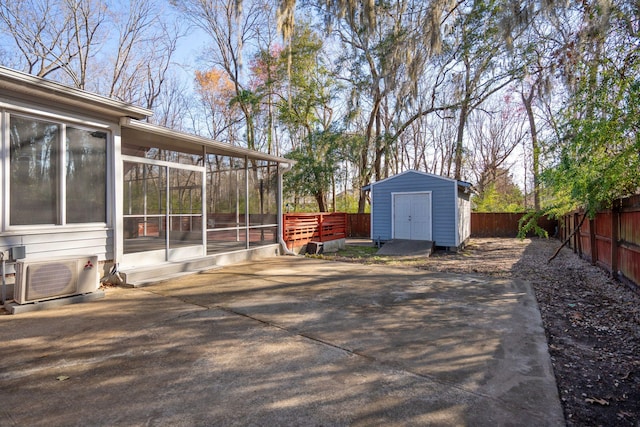 view of patio / terrace featuring a sunroom, a fenced backyard, an outdoor structure, ac unit, and a shed