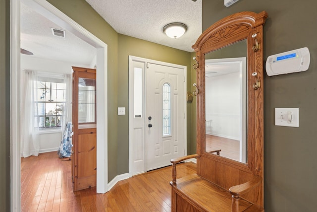 entryway featuring a textured ceiling, visible vents, light wood-style flooring, and baseboards