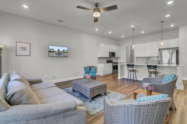 living room with light hardwood / wood-style floors and ceiling fan