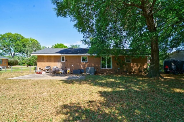 rear view of house with a yard, fence, and a patio
