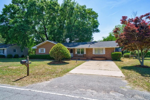 single story home with concrete driveway, a porch, brick siding, and a front lawn