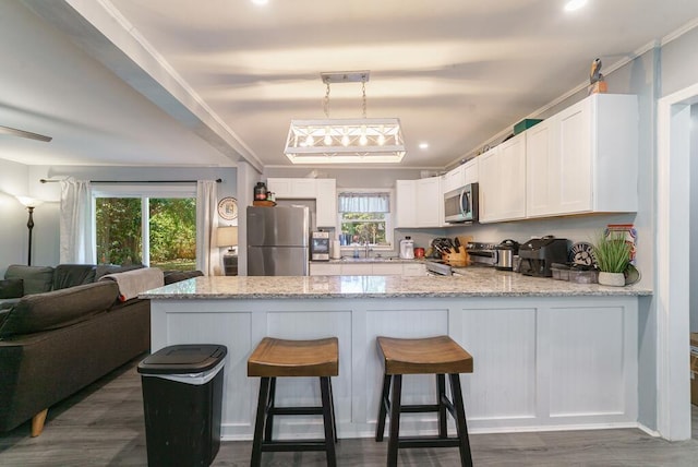kitchen with a peninsula, appliances with stainless steel finishes, dark wood-type flooring, and white cabinets