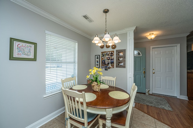 tiled dining space with crown molding, a textured ceiling, and a notable chandelier