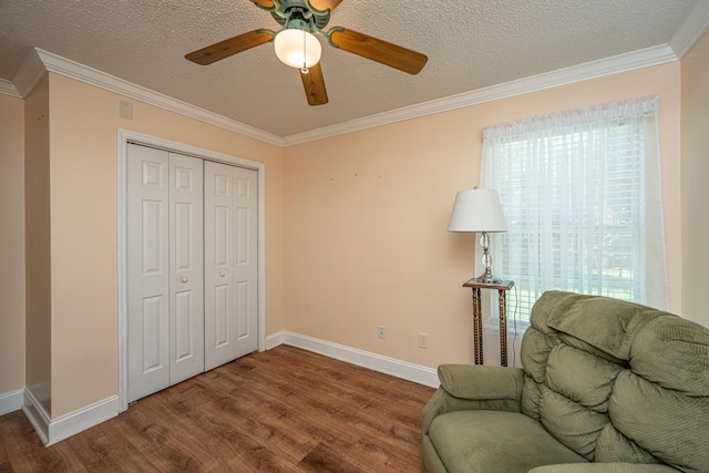 living area featuring ornamental molding, wood-type flooring, ceiling fan, and a textured ceiling