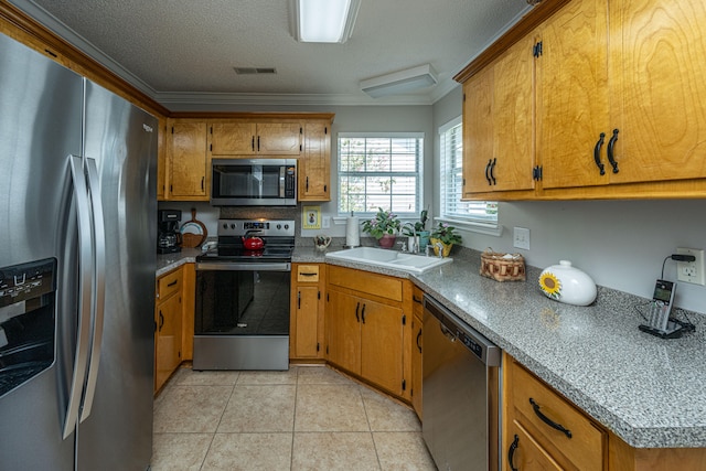 kitchen with stainless steel appliances, sink, light tile patterned floors, a textured ceiling, and ornamental molding