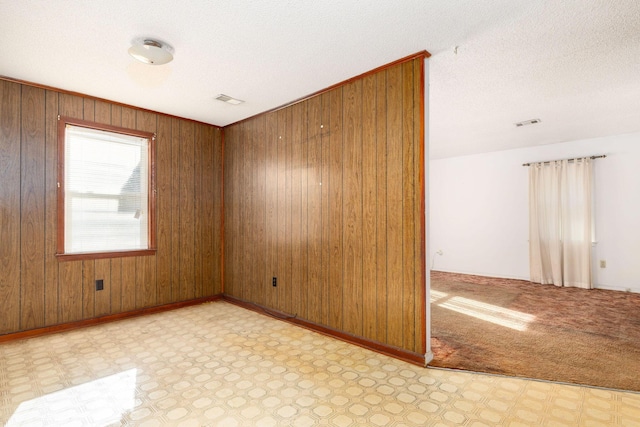 spare room with a textured ceiling and wood walls