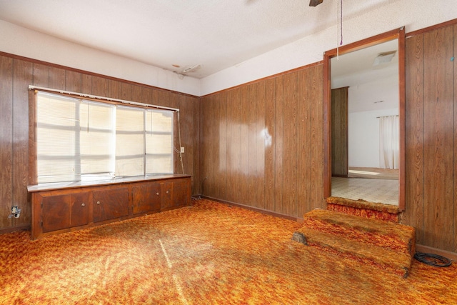 spare room featuring carpet flooring and wooden walls